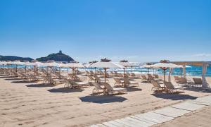 奇亚Conrad Chia Laguna Sardinia的海滩上的一排椅子和遮阳伞