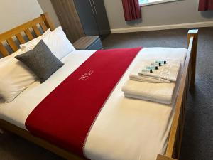 乔利The Hinds Head Hotel的一张铺有红白毯子和毛巾的床