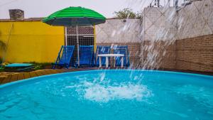 沙帕达-杜斯吉马朗伊斯Pousada Portal的一个带绿色遮阳伞和椅子及桌子的游泳池