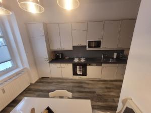 塞默灵Apartment Mohr am Semmering的厨房铺有木地板,配有白色橱柜。