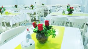 贝伦艺佩酒店的一间设有白色桌子的房间,一个花瓶上挂着玫瑰花