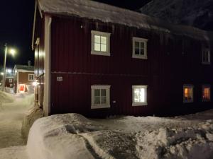 莫舍恩Sjøgata Riverside Rental and Salmon Fishing的一座红色的建筑,晚上四处下雪