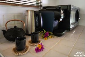 波拉波拉Villa Noa Noa - Matira的厨房柜台配有咖啡壶和一些鲜花