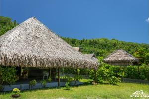 波拉波拉Villa Noa Noa - Matira的草丛中带草伞的两座小屋