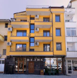 桑丹斯基Guest House Velik的街道上带阳台的黄色建筑