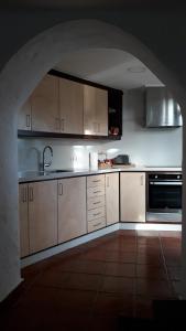 TafiraCasa cueva Bandama con jacuzzi的厨房配有白色橱柜、水槽和拱门。