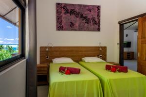 波拉波拉FARE ATEA的配有绿床单和红色枕头的客房内的两张床