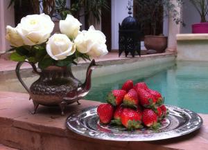 马拉喀什Riad Mandalay的一盘草莓和一束白玫瑰花