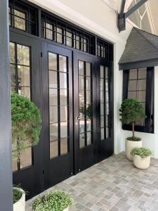 万隆Cottonwood Boutique Heritage Otten的黑色前门,带窗户和盆栽植物