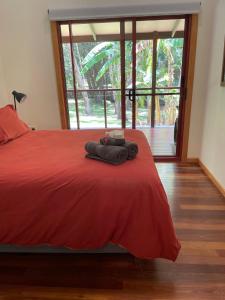 Kin KinKin Kin Cottage Retreat的一间卧室设有红色的床和大窗户