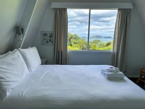 科罗曼德镇Pohutukawa Coastal Chalets的卧室配有白色的床和大窗户