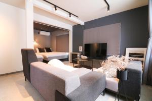 札幌Guest house SUMIKAWA的客厅配有两张床、一张沙发和一台电视
