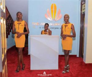 基苏木The VIP Luxury Lounge Hotel的站在讲台后面的三个穿着橙色衣服的妇女