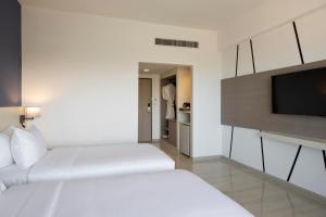 七岩Centara Life Cha-Am Beach Resort Hua Hin的酒店客房设有两张床和一台平面电视。