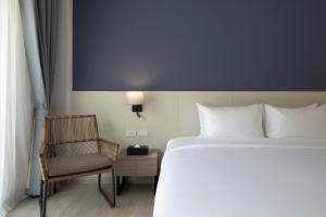 七岩Centara Life Cha-Am Beach Resort Hua Hin的在酒店房间的床和椅子
