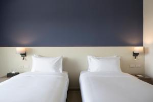 七岩Centara Life Cha-Am Beach Resort Hua Hin的两张睡床彼此相邻,位于一个房间里