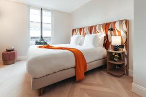 巴黎Padam Hôtel的一间卧室配有一张大床,上面有橙色毯子
