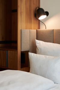 慕尼黑科库恩塞德林格托酒店的一间卧室配有一张带白色床单和一盏灯的床。