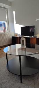 卢森堡Core Luxembourg City的客厅设有玻璃咖啡桌,配有电视