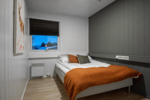 摩城Skillevollen Motell的一间卧室配有一张带橙色毯子和窗户的床。