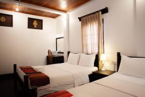 琅勃拉邦Villa Senesouk Luang Prabang的酒店客房设有两张床和窗户。