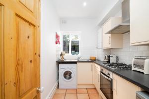 伦敦Beautiful & Cosy 1-Bedroom Apartment in Clapham的厨房配有洗衣机和烘干机