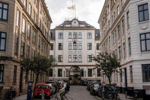 哥本哈根亚瑟库隆酒店的一个人在建筑物前骑着自行车