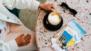 雅典Mosaikon Glostel的坐在桌子旁喝杯咖啡的女人