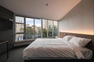 首尔Pillowsopher Hongdae的一间卧室设有一张大床和一个大窗户