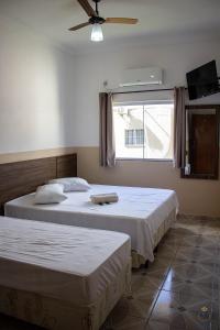 阿帕雷西达Pousada Bela Rainha的卧室设有两张床、风扇和窗户。