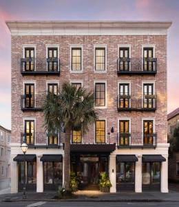 查尔斯顿The Palmetto Hotel, Charleston的一座砖砌的建筑,前面有棕榈树
