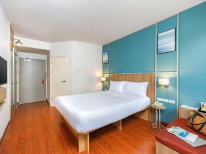 波普托Hotel Ibis Samui Bophut的蓝色墙壁的房间里一张大白色的床