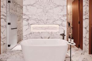科威特Grand Hyatt Kuwait的设有带白色浴缸的大理石墙浴室