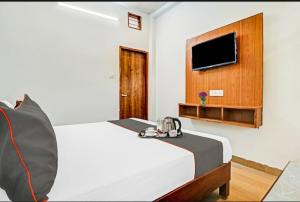德拉敦Hotel StudioZ Sahastradhara的一间卧室配有一张床,墙上配有电视