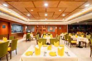 杜尔加布尔Fortune Park Pushpanjali, Durgapur - Member ITC's Hotel Group的餐厅设有桌椅和黄色餐巾