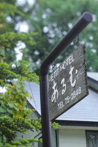 白马村HakubaGoryu Pension&LogCottage Arumu的房屋前的柱子上的标志