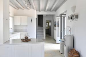 帕罗斯岛SUNRAY Paros Beach front 2 bedroom house next to kite sports的白色的厨房配有白色橱柜和冰箱。