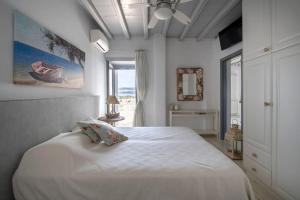 帕罗斯岛SUNRAY Paros Beach front 2 bedroom house next to kite sports的卧室配有白色的床和窗户。