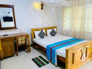 阿努拉德普勒Rich Resort & Restaurant的一间卧室配有一张床、一张书桌和一面镜子