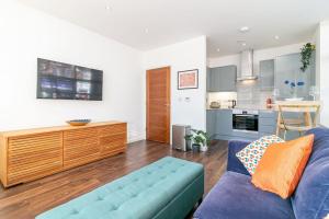 圣奥尔本斯*20% off Monthly* St Albans City Centre Apartment的一间带蓝色沙发的客厅和一间厨房