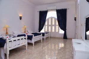 卢克索Luxor Oasis Guest House的一间卧室设有四张床、一个水槽和窗户