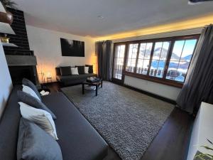 RuerasCasa Ucliva - Charming Alpine Apartment Getaway in the Heart of the Swiss Alps的带沙发和大窗户的客厅
