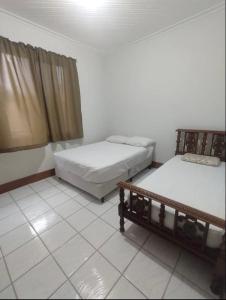 塞拉内格拉Casa no Centro de Serra Negra的客房设有两张床,铺有瓷砖地板。