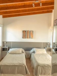 拉法尔达Good Life Resort的配有白色墙壁和木制天花板的客房内的两张床
