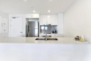 达尔文Luxury two-beds harbour views apartment的厨房配有白色橱柜和不锈钢冰箱