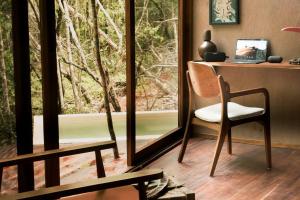 图卢姆OJO DE AGUA. Design+pool. Vive la auténtica selva!的客房设有书桌、椅子和窗户。