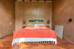 图卢姆OJO DE AGUA. Design+pool. Vive la auténtica selva!的一间卧室配有一张带橙色毯子的大床