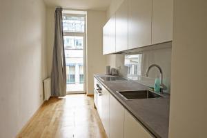 维也纳Vienna Living Apartments - Ottakring的厨房配有白色橱柜、水槽和窗户。