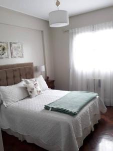 圣米格尔·德·图库玛Muy agradable departamento. Bien ubicado, luminoso的一间卧室配有一张带白色床单的床和一扇窗户。