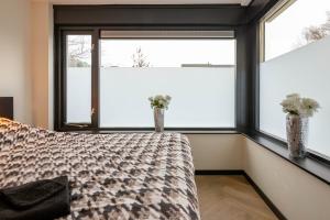莱利斯塔德Luxe Studio Liemers的一间卧室设有一张床和两个窗户。